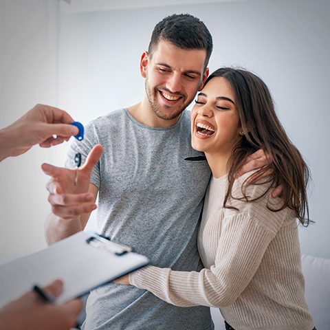 Real estate agent handing over the keys to a happy couple